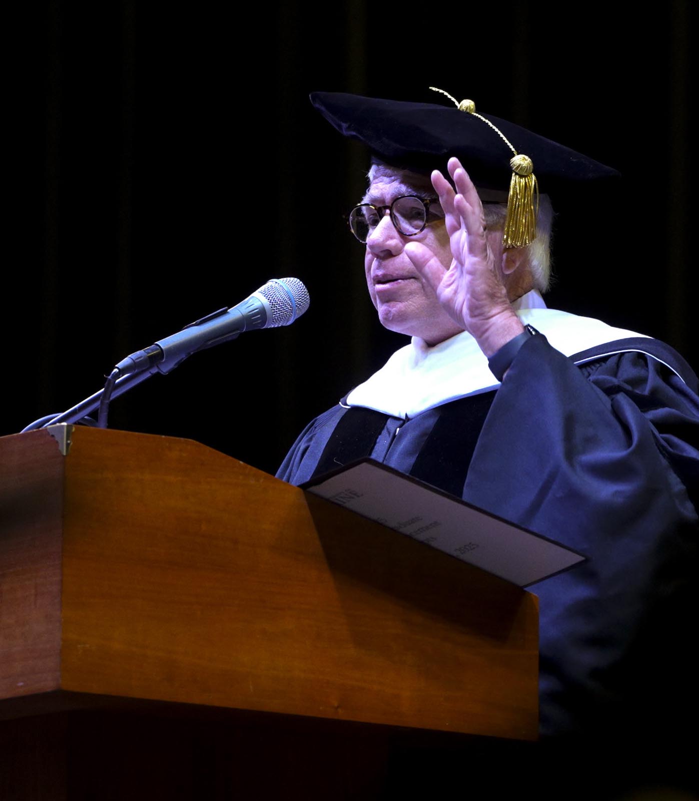 A photo of Robert Dana speaking at a podium during commencement