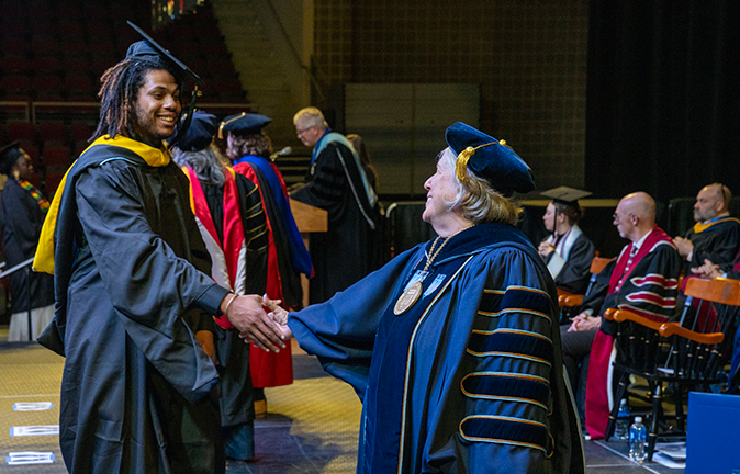 A photo of a graduate shaking hands with the president