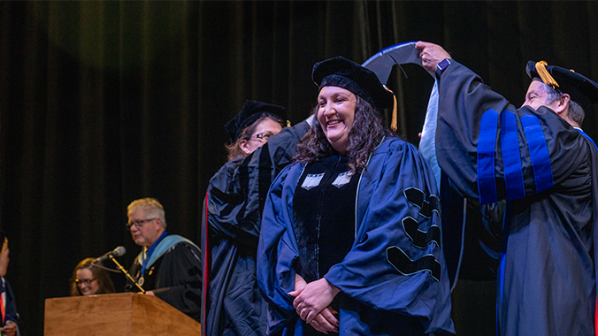 A doctoral candidate getting hooded at commencement