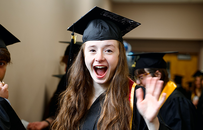 A photo of an excited graduate waving