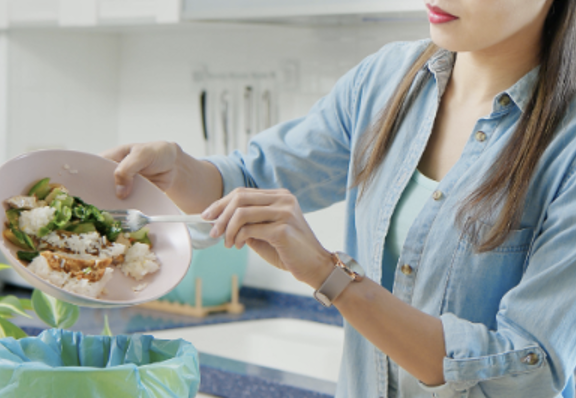 Woman scraping a plate of food into the trash