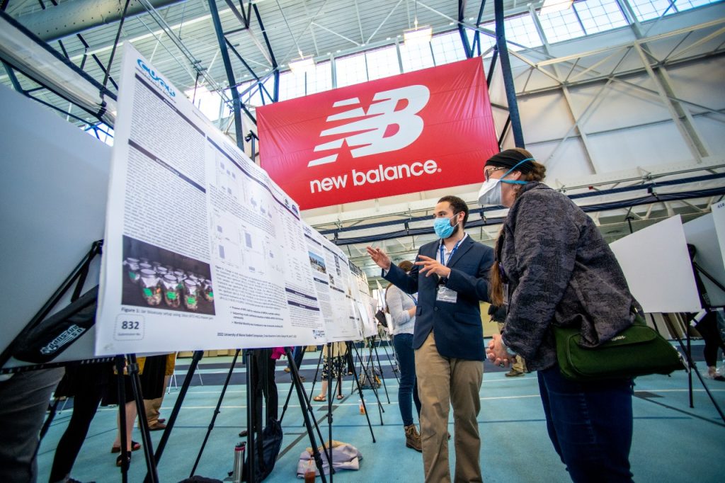 Image of two individuals in front of a poster