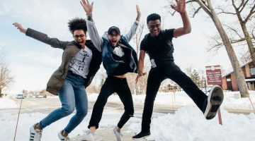 three people jumping outdoors on a snowy day