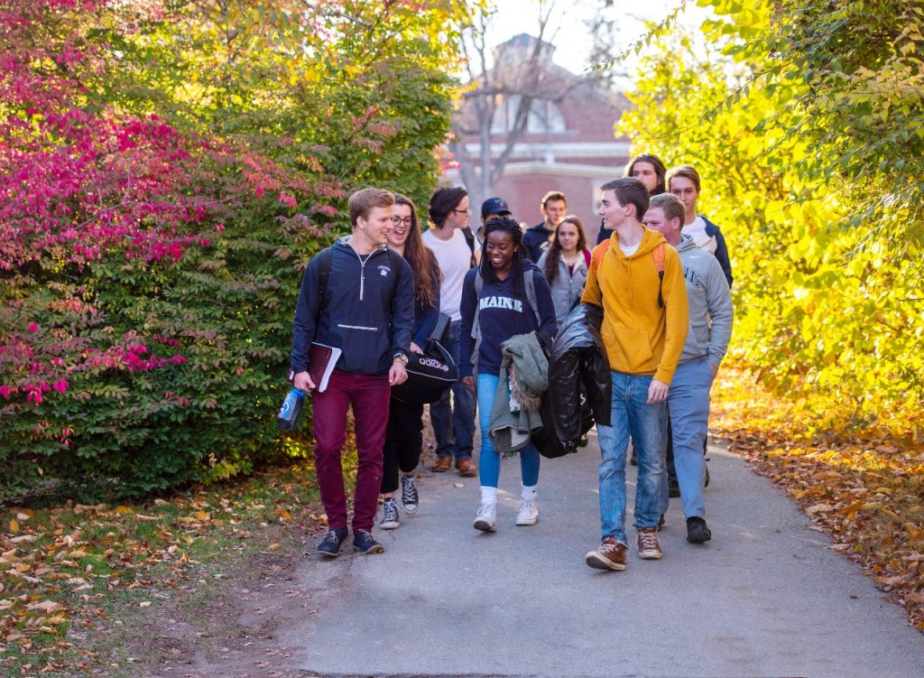 Happy students walking through UMaine campus