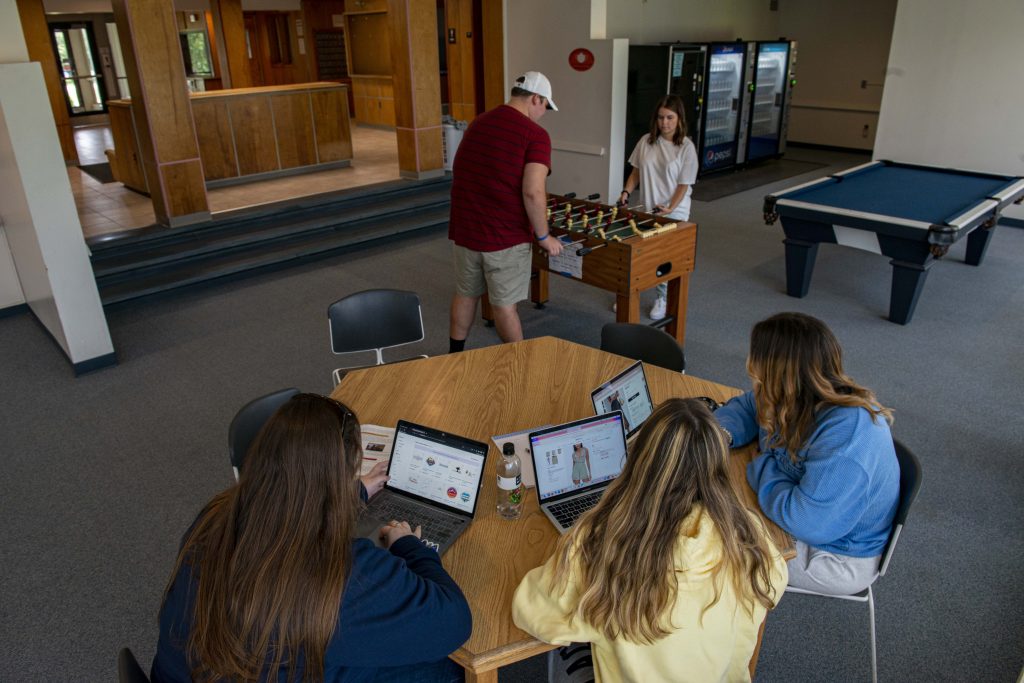 Smiling students playing foosball and relaxing in Pensobcot Hall lounge