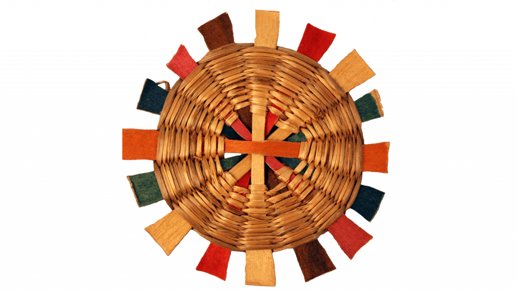 Image of a circular object made with colorful crossed elements woven together with grass.