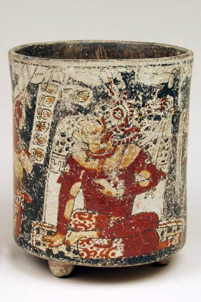 Vase on small tripod feet and with vertical sides. Painted with intricate image of a seated person with an elaborate headdress.