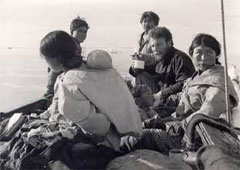 An image of a Caucasian man (Emerick) sitting casually and chatting with a group of Inuit outside.
