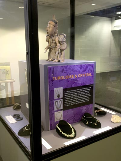Image of a museum case with a ceramic statue and jewelry exhibited.