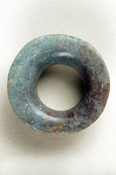 Ring-shaped ornament carved of jade that fades in color from light teal on the left to mottled rich brown on the right.