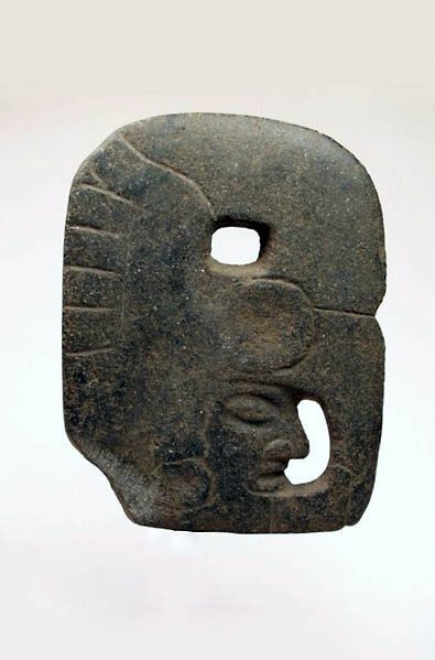 Carved stone object shaped as a face with a large headdress. 