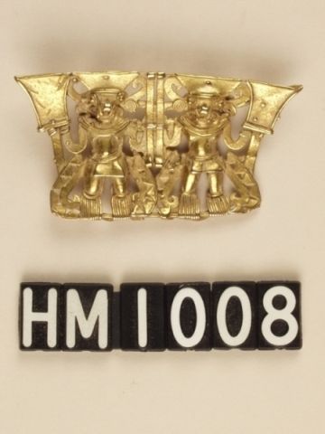 Golden ornament depicting a pair of anthropomorphic curly-nosed figures with headgear, possibly representing bats, holds standards. Decorated streamers hang from their waists.