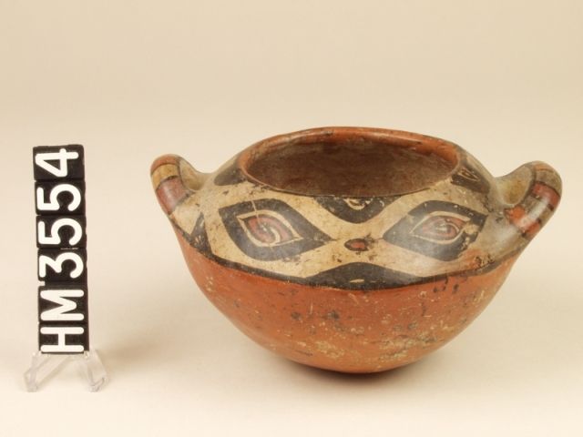 Polychrome ceramic bowl with handles. The sequence of black ovals in the top band of this bowl suggests the sequence of ovals in the markings of the boa constrictor. Each oval also contains an abstract figure in red, indicating that boa ovals, viewed as fertilized eggs, are the source of life forms.