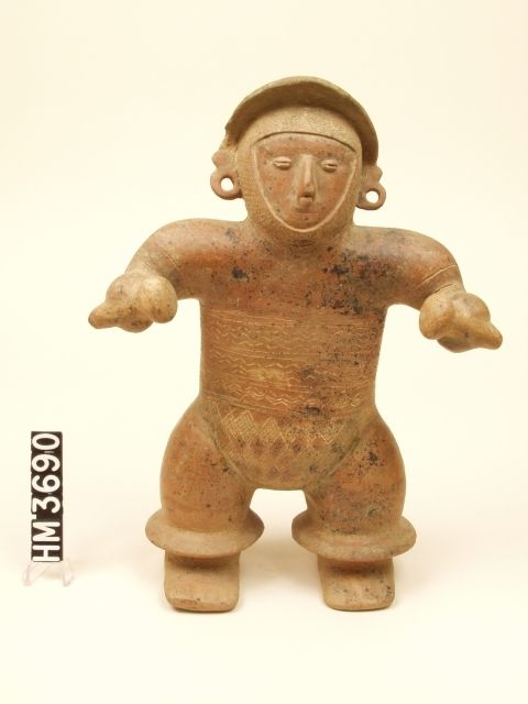 Ceramic standing figure with hat and ear spools holding rattles in each hand.