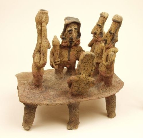 Ceramic object depicting a group of figures on a platform.