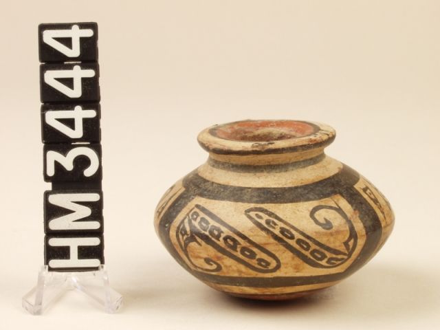 Globular bottomed miniature vessel with narrow neck and flared mouth. Mouth painted red with black border and neck has black stripe. Thick black lines offset geometric designs with detailed turtle (eyes, nostrils, mouth, front feet with claws, tail, and back feet with claws). On sides there are lines with ovals painted inside them and curly lines coming off the ends. Bottom painted red.