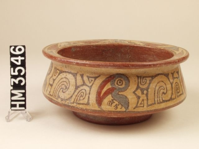 Polychrome ceramic bowl decorated with abstract Y-elements and a more naturalistic jaunty purple bird with a long, colorful bill, suggesting a toucan.