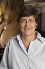 Image of a caucasian woman with short brown hair wearing a pale button-up shirt.