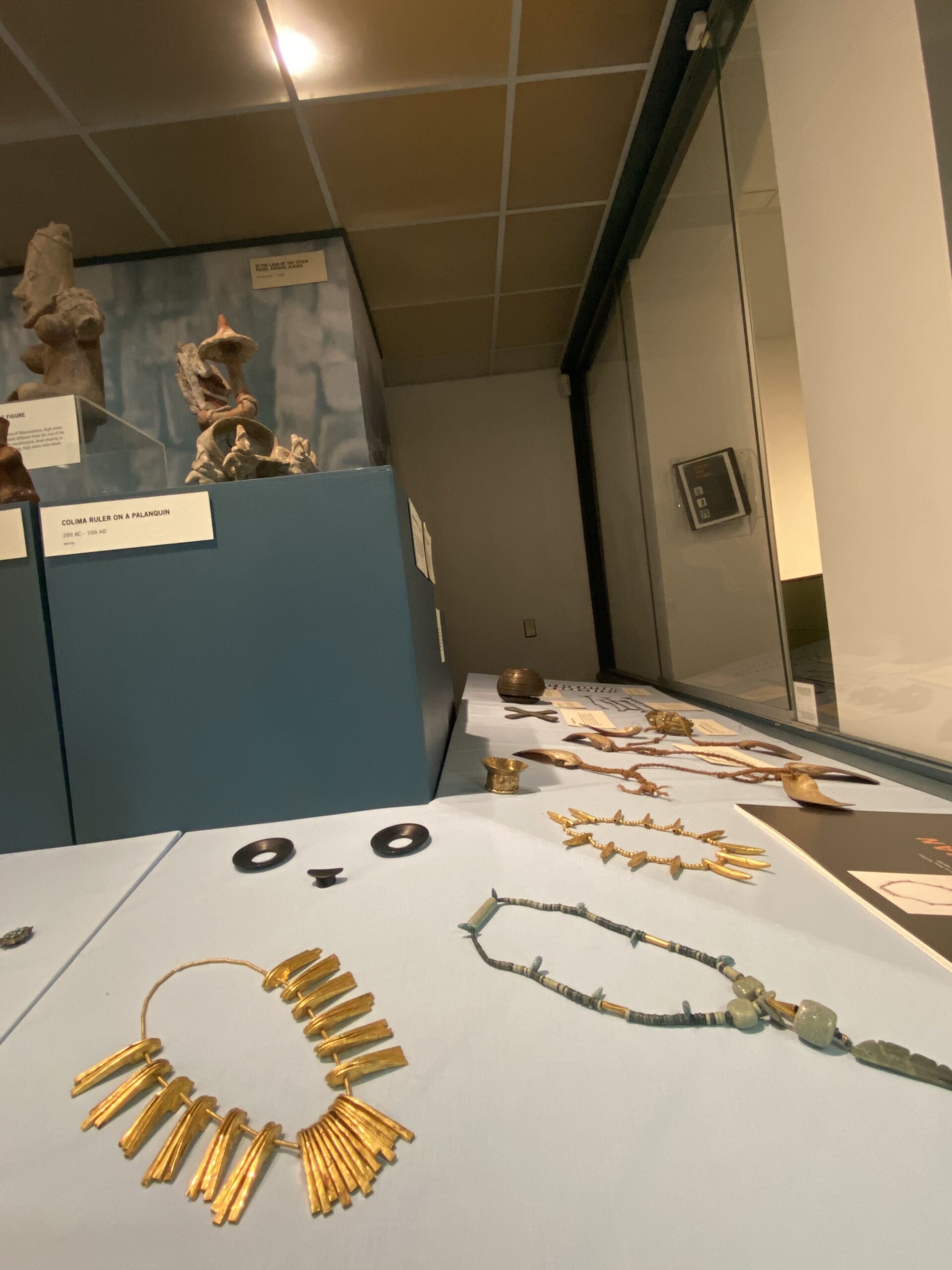 Jewelry on exhibit - necklaces of gold and jade, obsidian objects for ears and lip.