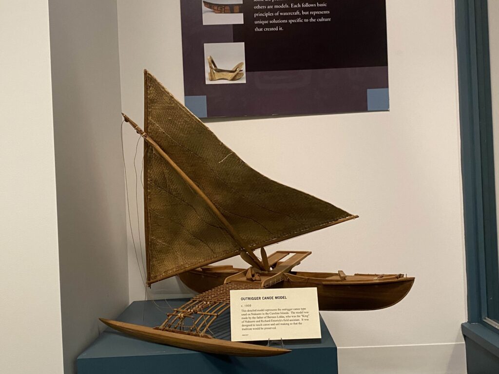 Image of a model canoe with triangular sale and single outrigger.