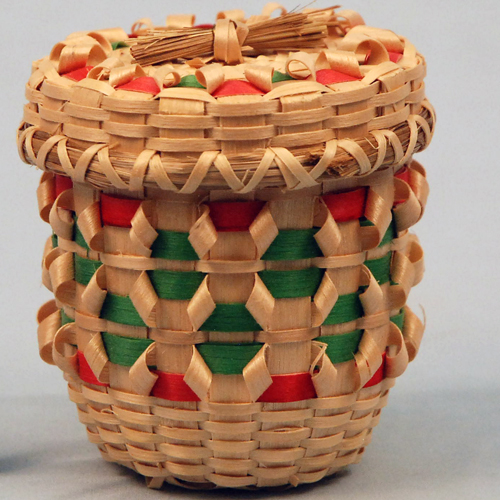 Small decorative basket with curl decorations and red and green elements.