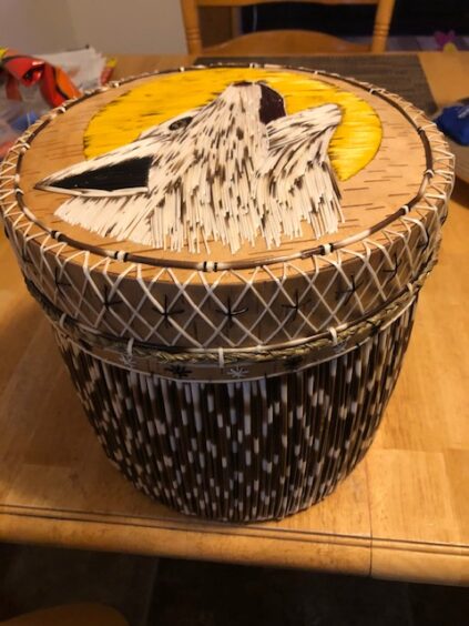 Birchbark container decorated with porcupine quills. The cover features a howling wolf.