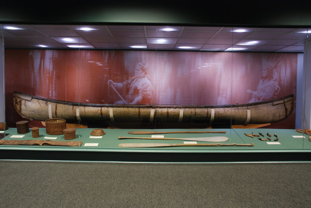 Image of a birchbark canoe in a museum case.
