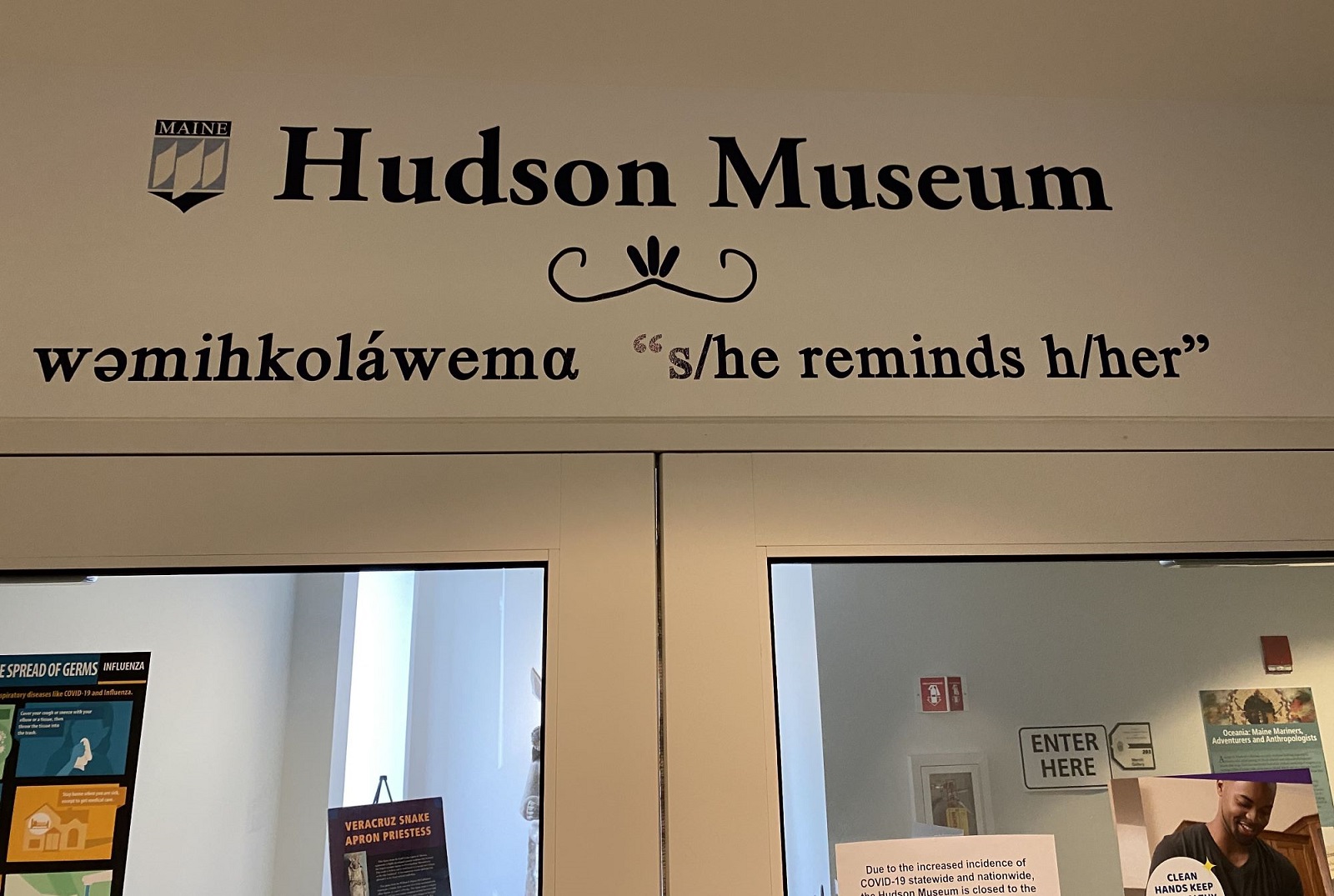 Image of signage above a doorway. The sign indicates the location in both English and Penobscot.