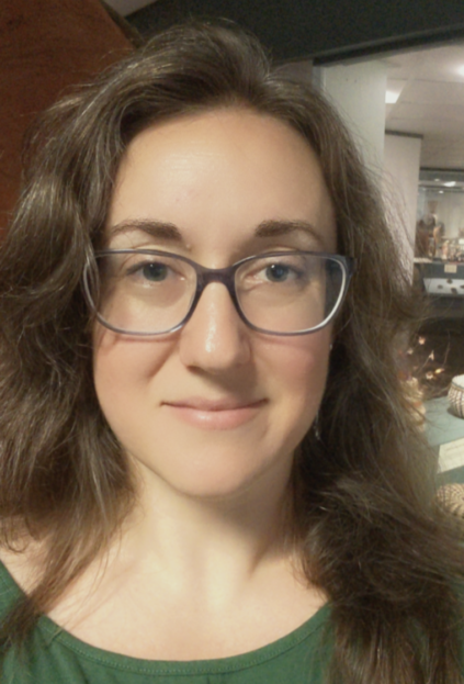 Image of a caucasian woman with long brown hair and glasses wearing a green top.