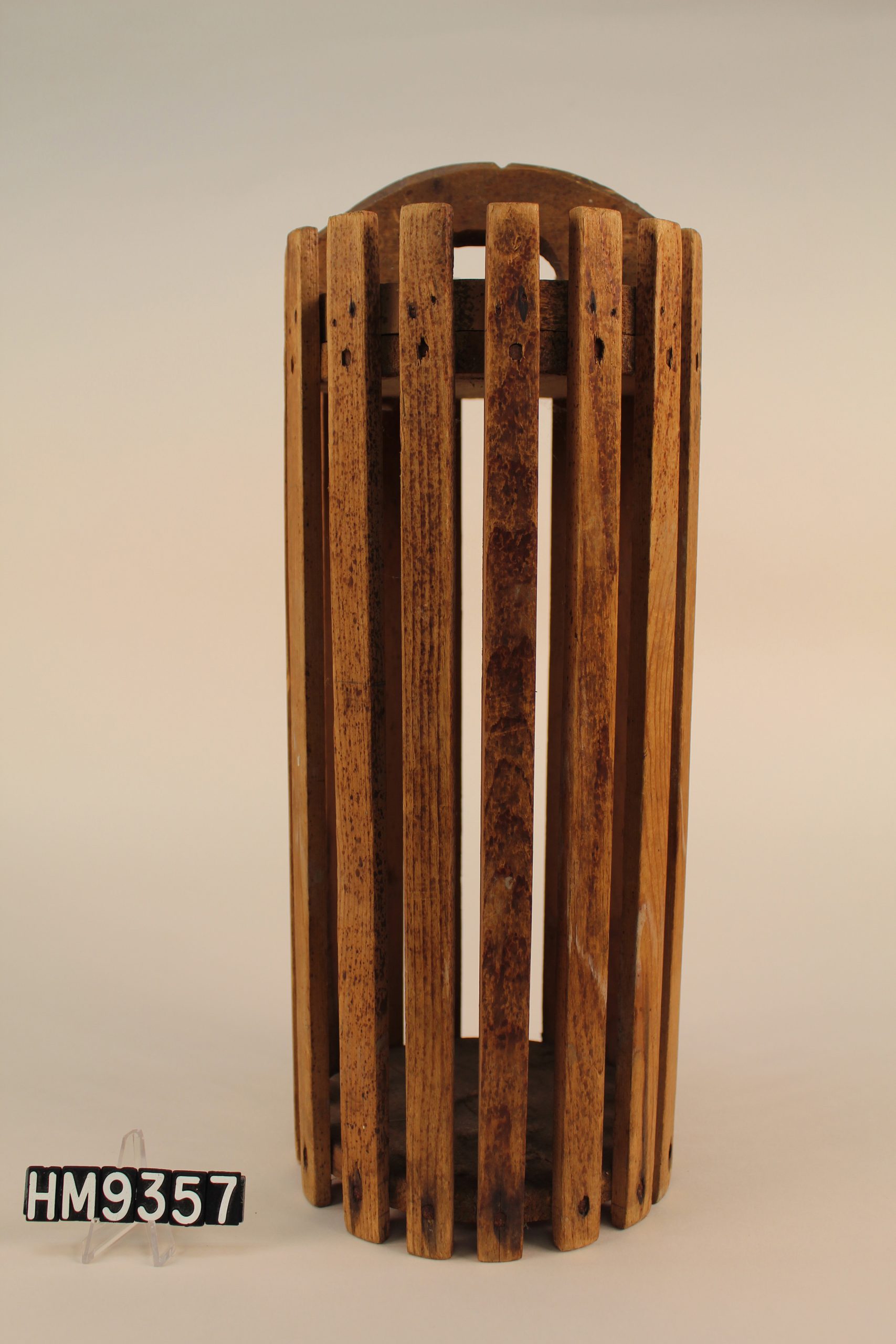 Image of tall, cylindrical mold with slats and a handle on top.