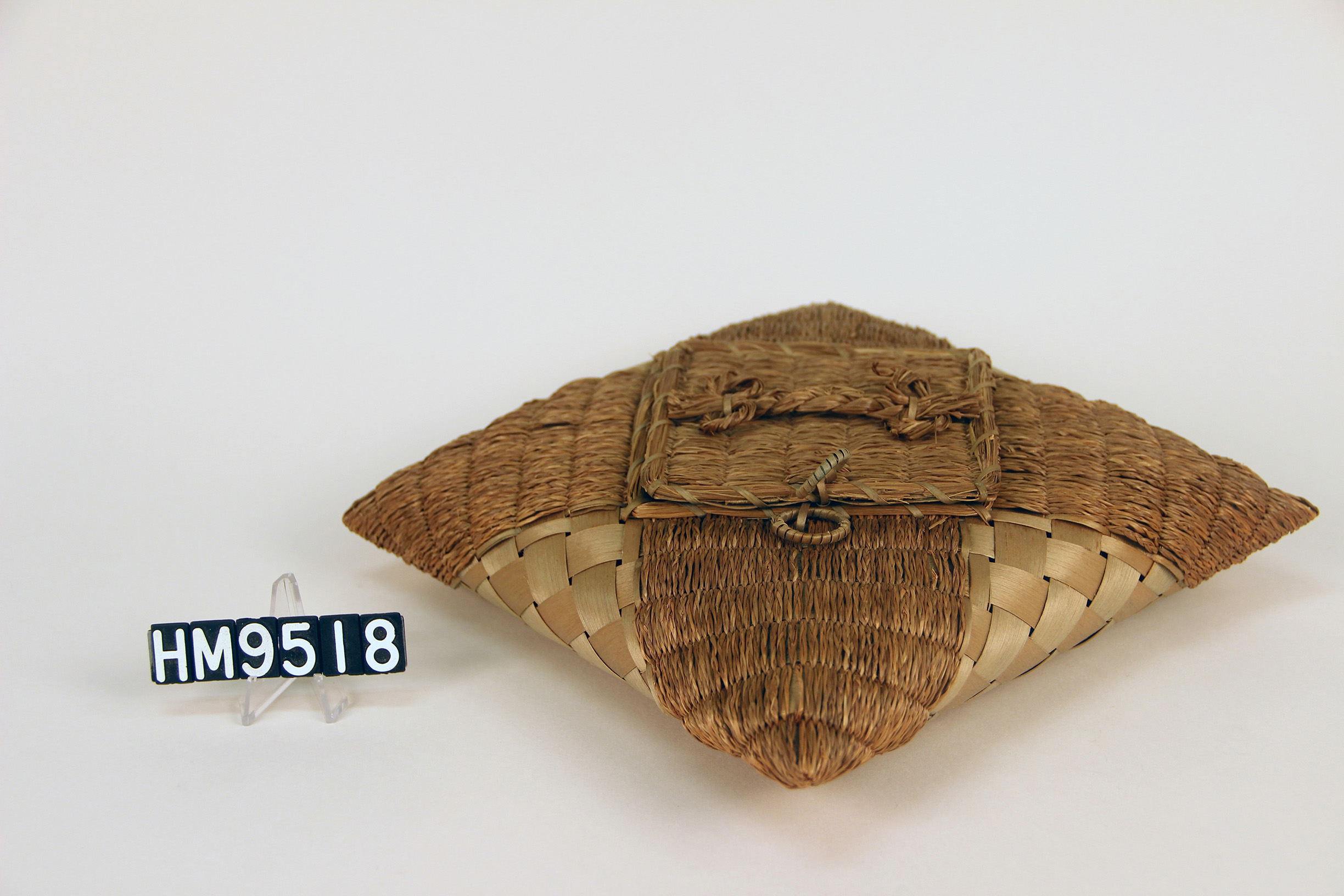 Square, pillow-shaped basket with braided sweetgrass details.