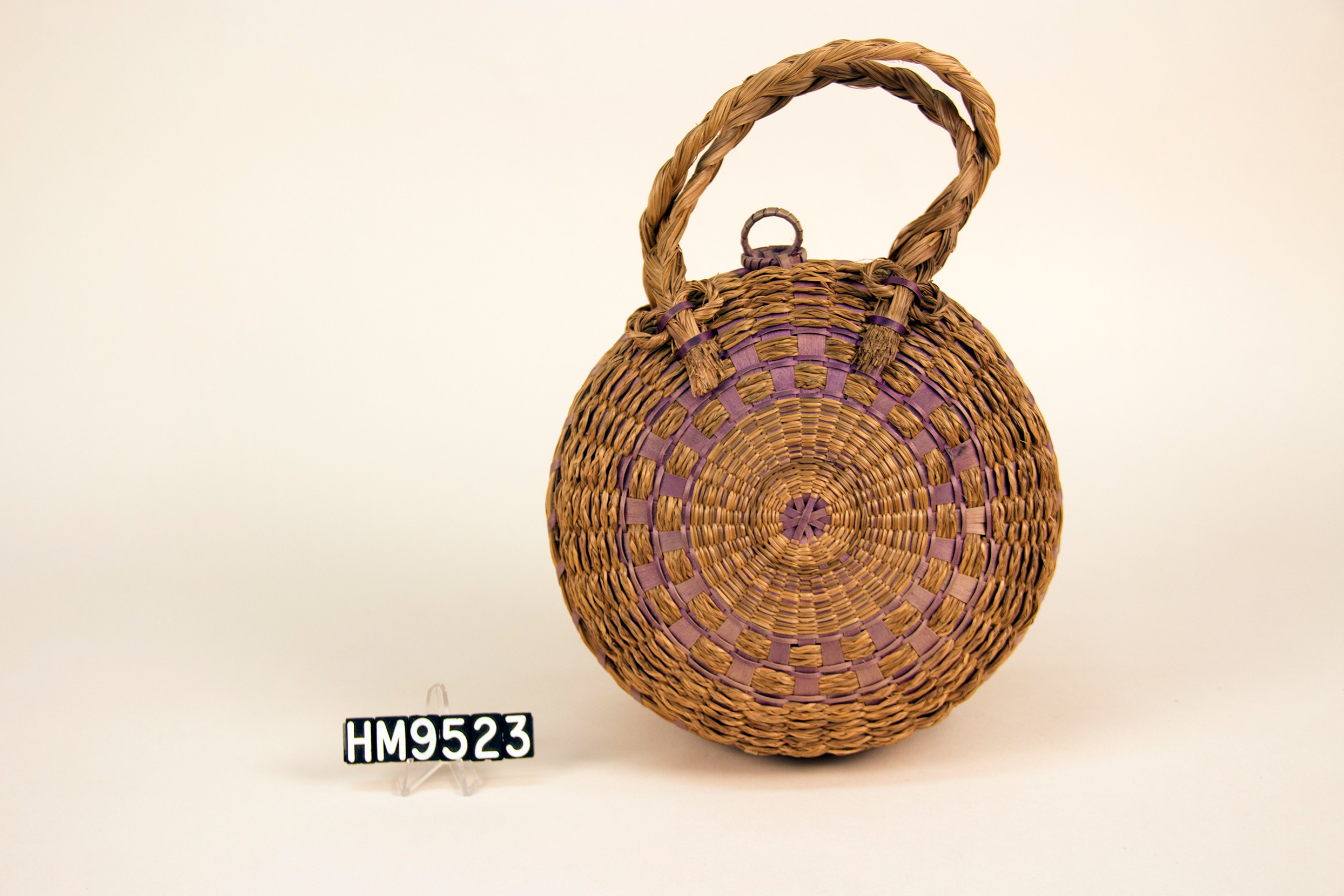 Image of a circular purse basket with two braided handles and ring closures.