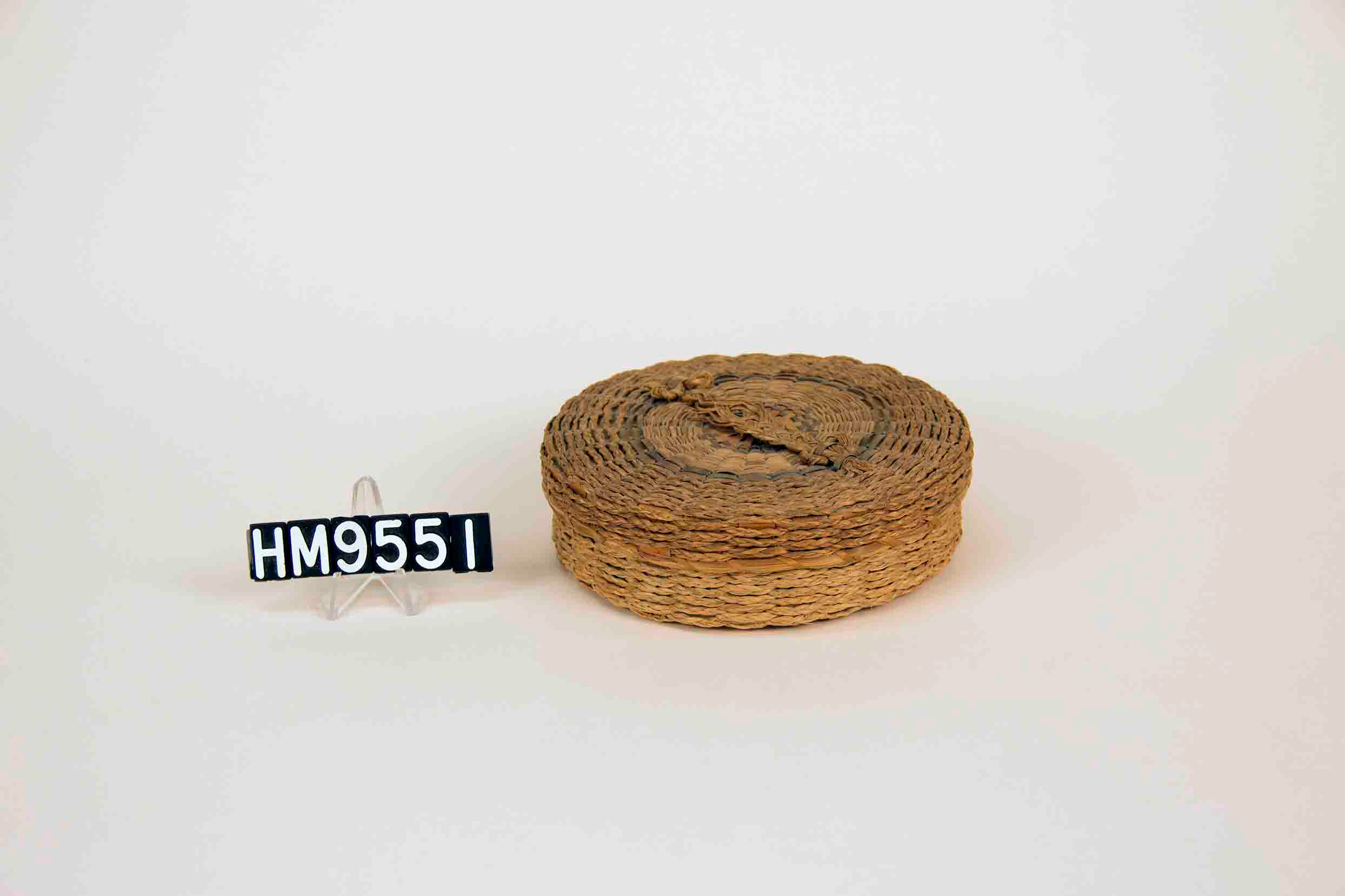 Image of small, round basket with braided handle on cover.