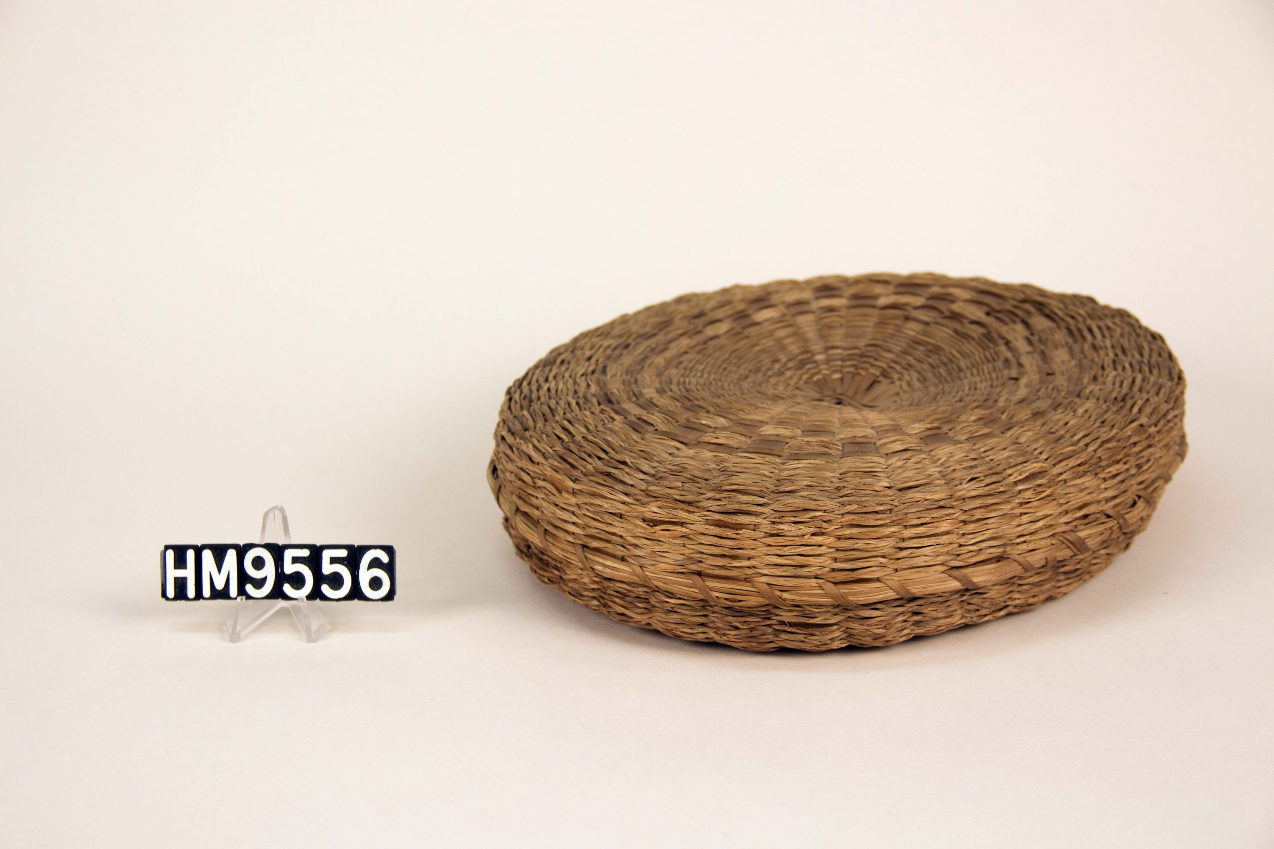 A small disc-shaped braided sewing basket.