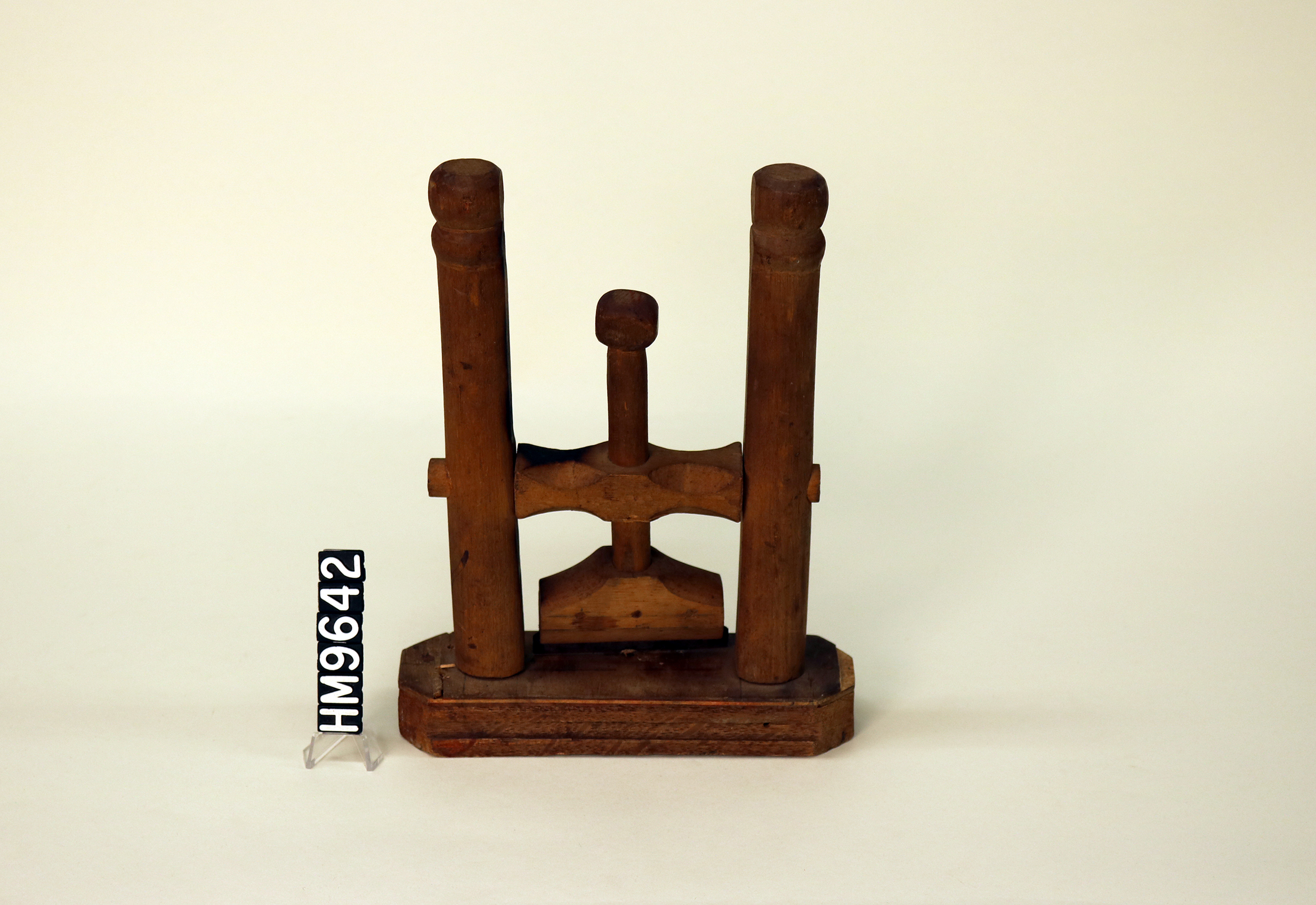 Image of a wooden implement with a base, two arms, and a portion in the center that pivots on a cross-piece.