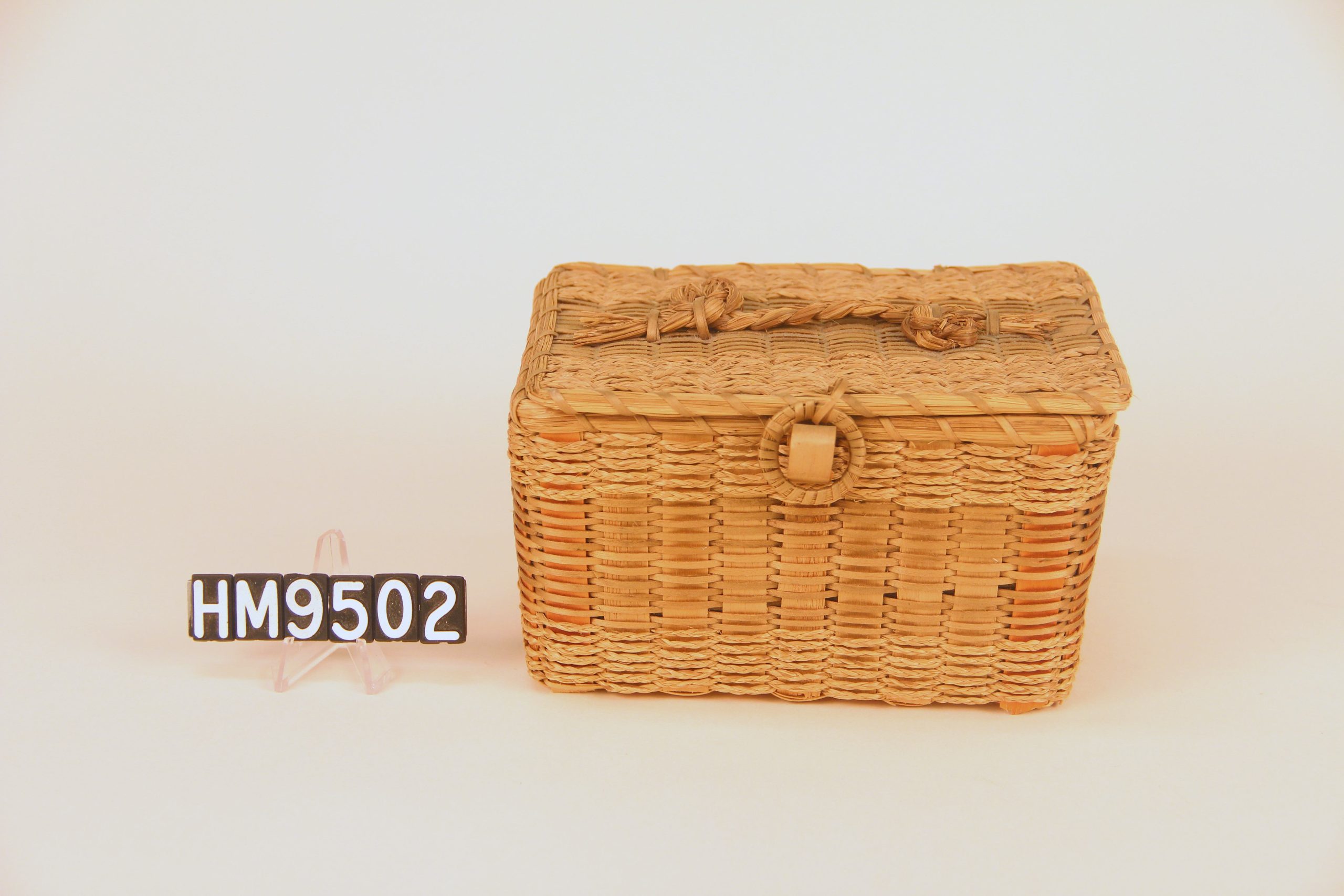 Image of rectangular basket with ring closure and braided sweetgrass handle.