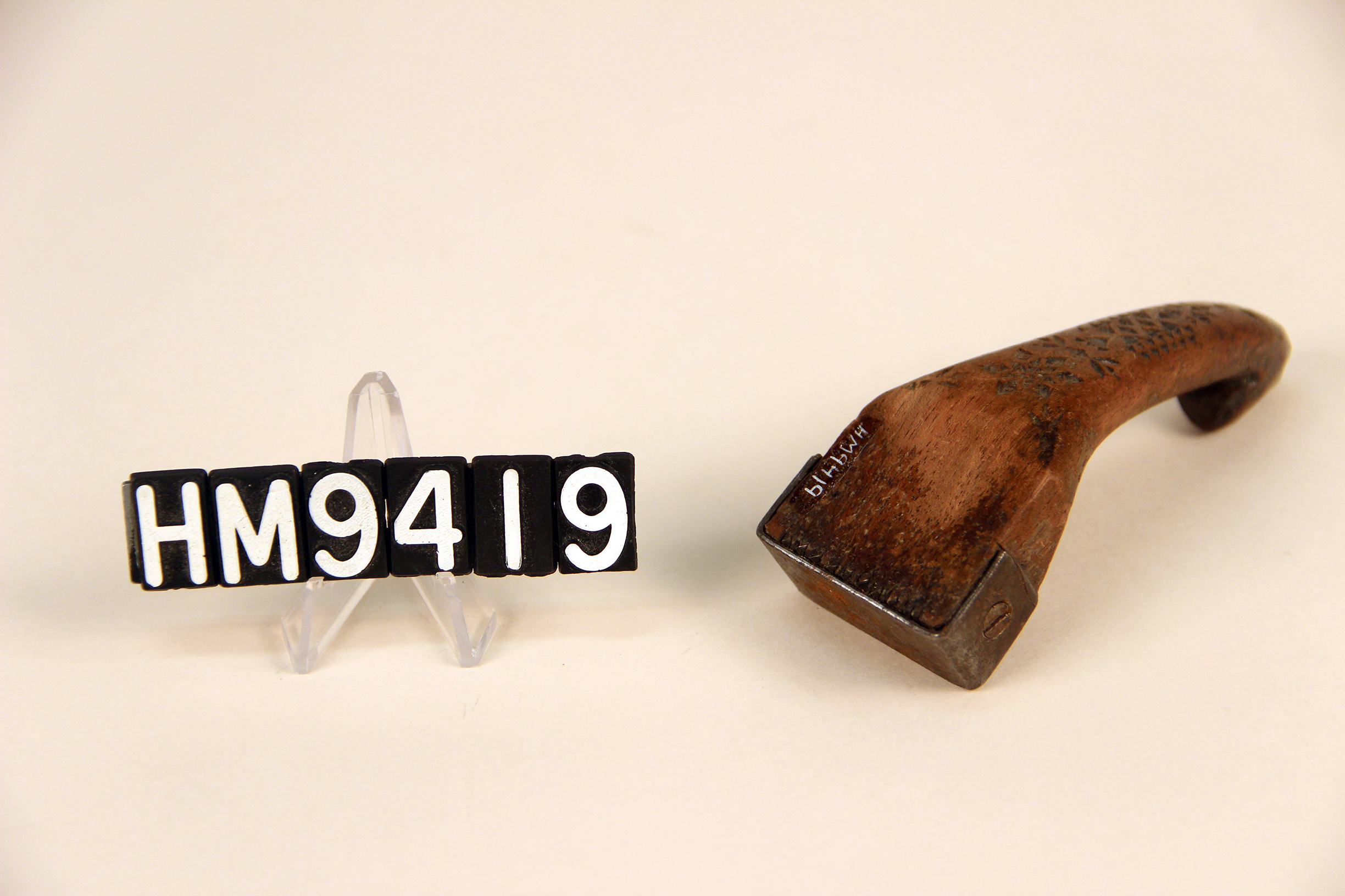 Image of a wooden implement forming a handle to which thin metal teeth are attached.