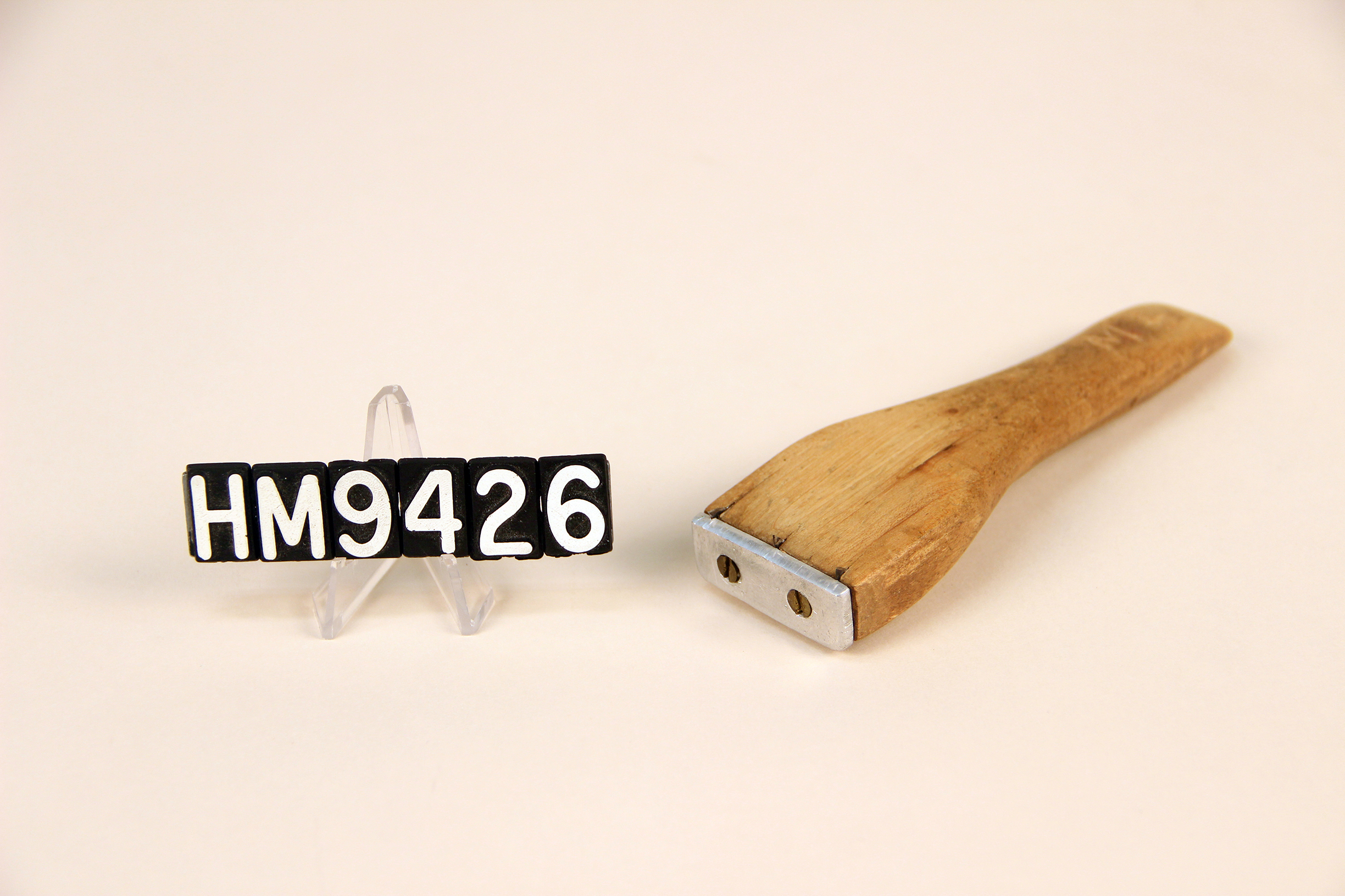 Image of a wooden implement forming a handle to which thin metal teeth are attached.