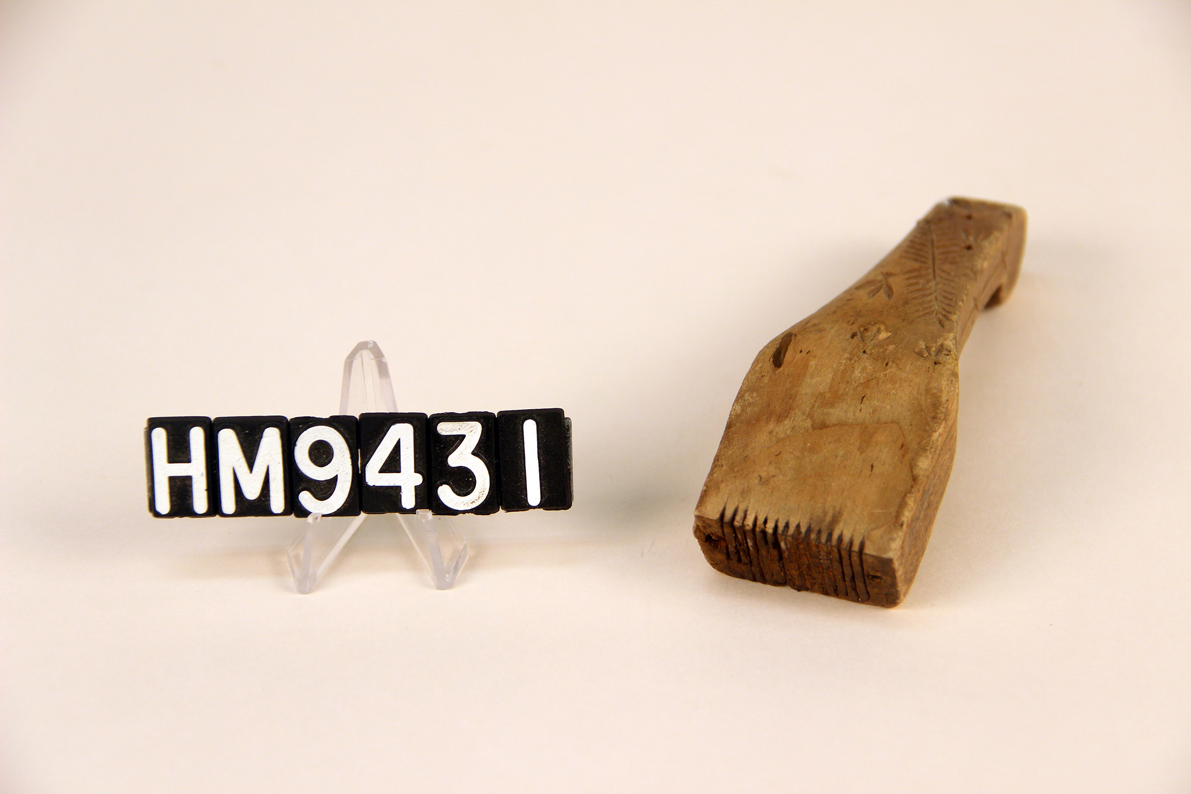 Image of a wooden implement forming a handle to which thin metal teeth are attached.