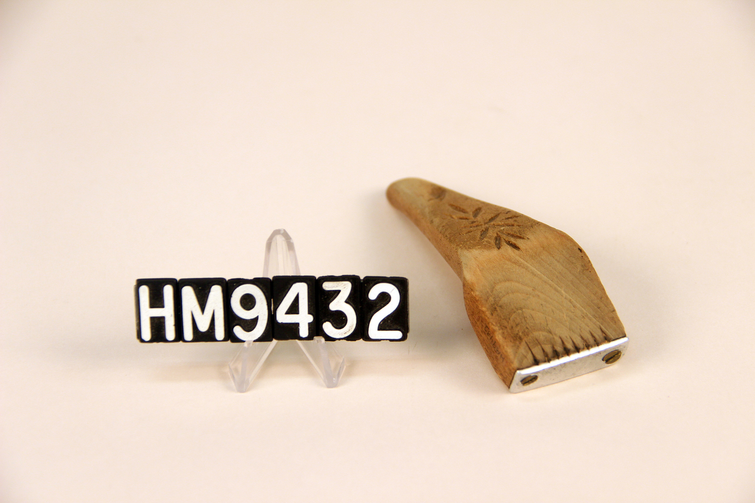 Image of a wooden implement forming a handle to which thin metal teeth are attached.