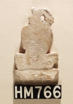Image of a seated figure made of shell with incised details.