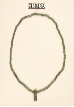 Image of necklace made with tublar greenstone beads and an elongated greenstone ornament.