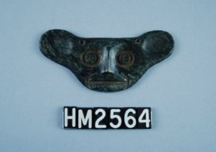 Small ornament made of dark green stone in the shape of an animal with large ears.