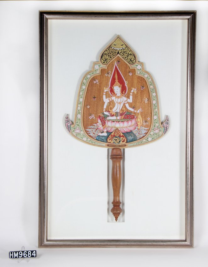 Image of a fan in a frame. The fan is wooden and is painted with a multi-armed deity.