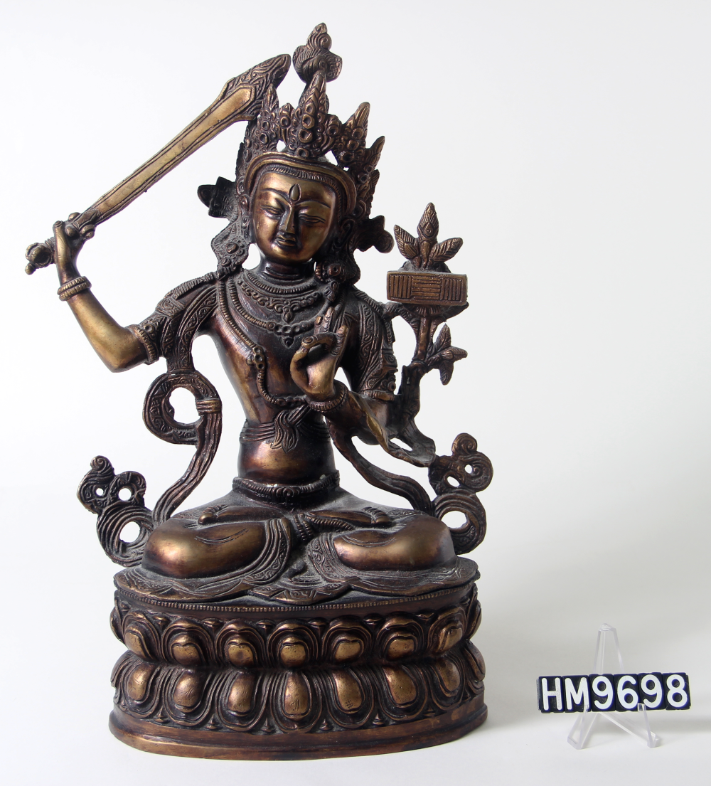 Cast bronze statue of deity sitting and holding a sword.
