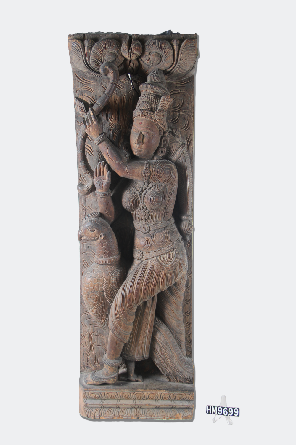 Carved relief of a female deity holding a bow and arrow and standing with a large bird.