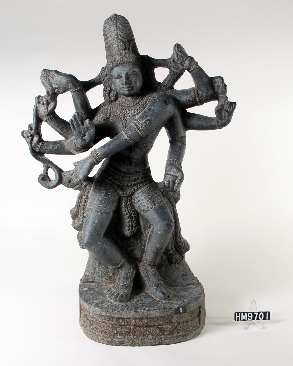 Carved stone statue of deity with eight arms dancing.