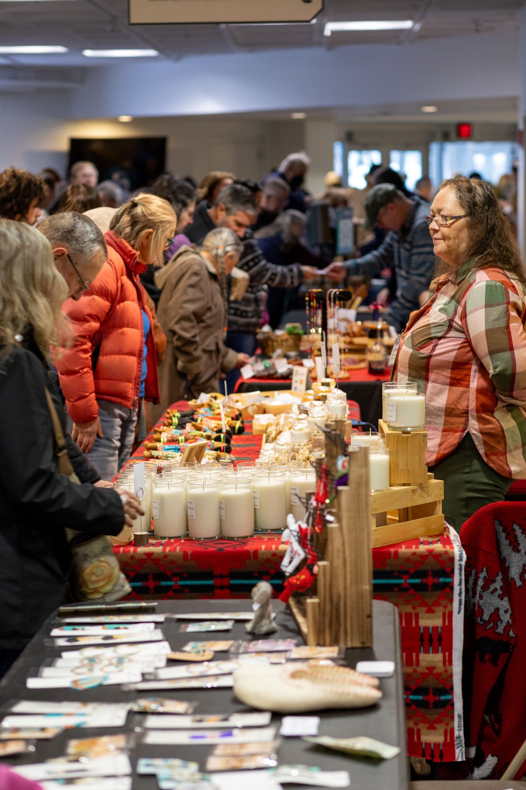 Image of tables at an indoor market with crowds of people.