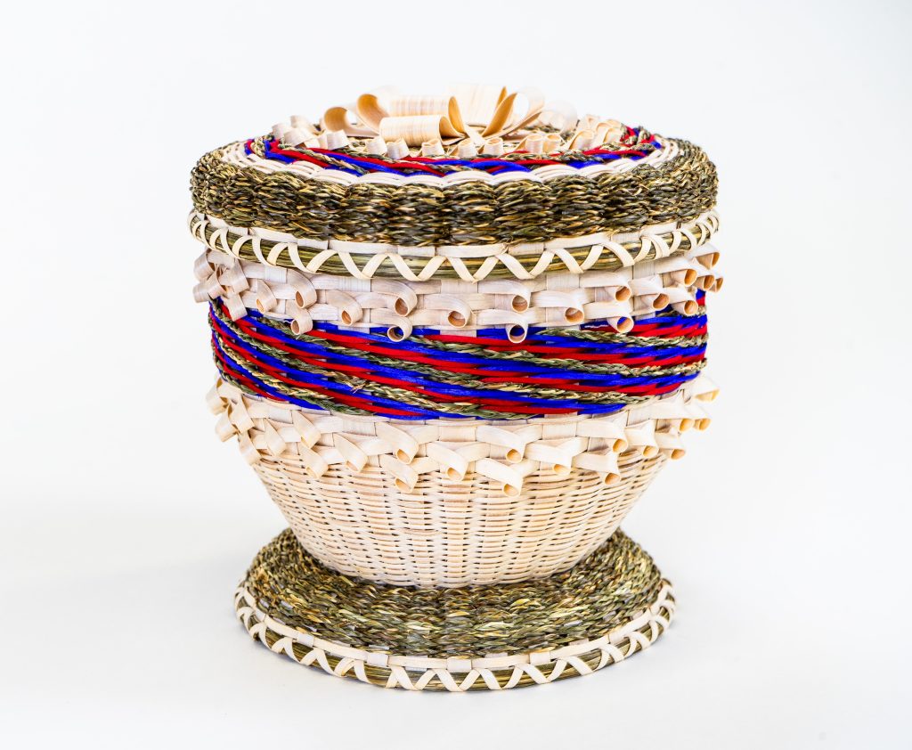 Image of a decorative basket with curls, finely-braided sweetgrass, and stripes in blue and magenta.