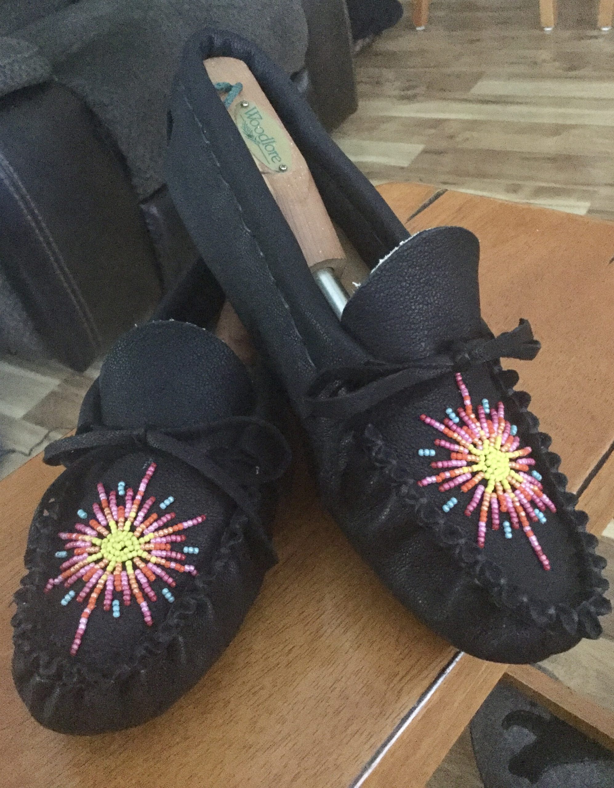 Image of black moccasins with colorful starburst beaded decoration.